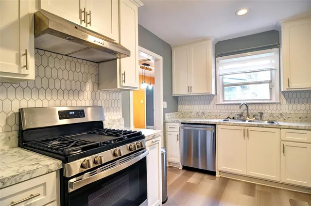a kitchen with a stove a sink and wooden floor