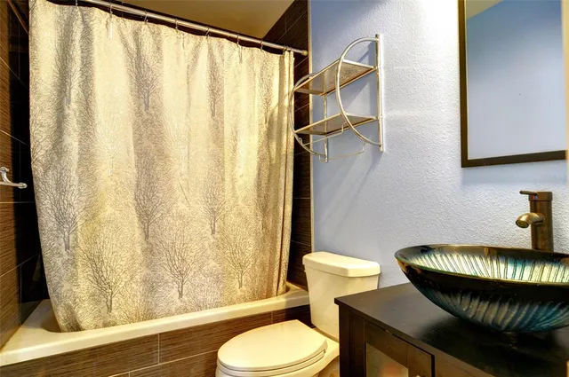 a bathroom with a granite countertop toilet and a sink