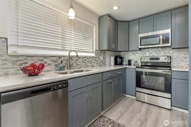 a kitchen with granite countertop a sink cabinets and stainless steel appliances