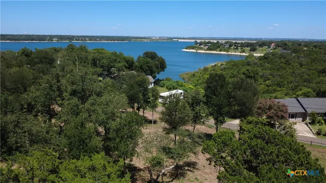 an aerial view of ocean with residential house with outdoor space and trees all around