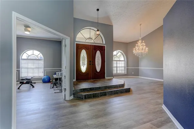 a view of an empty room with wooden floor and windows