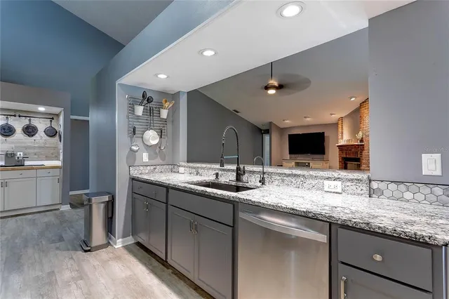 an empty room with wooden floor a kitchen view and a refrigerator