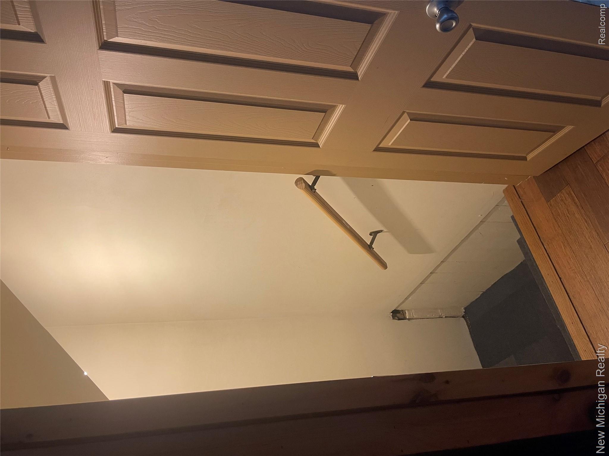 7415 Farrand Road Clio, MI 48420 - Photo 23 of 31 Stairwell entry featuring wood-finish flooring, a six-panel door with a silver-tone knob, and a light-toned handrail