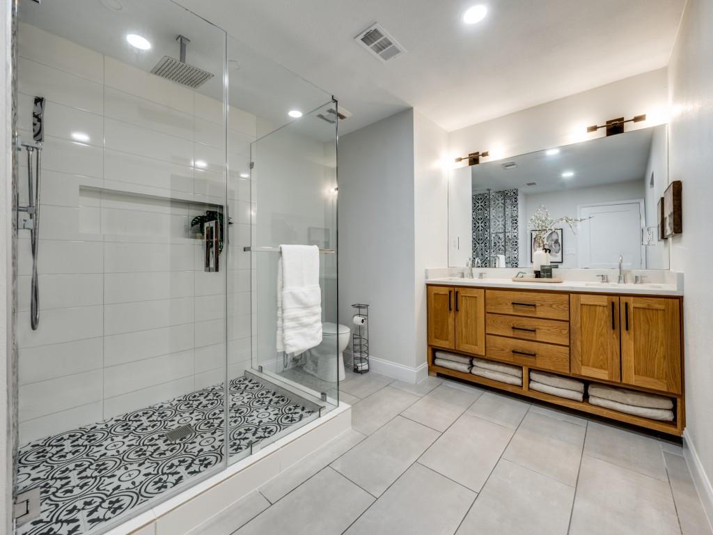 3406 Springwood Lane Dallas, TX 75233 - Photo 26 of 36 a bathroom with a glass door shower a sink and a mirror