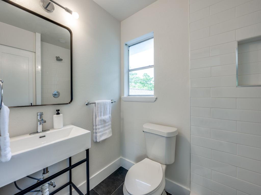 3406 Springwood Lane Dallas, TX 75233 - Photo 31 of 36 a bathroom with a toilet a sink a mirror and a window