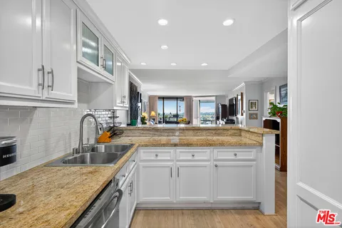 a kitchen with stainless steel appliances granite countertop a sink and cabinets with wooden floor