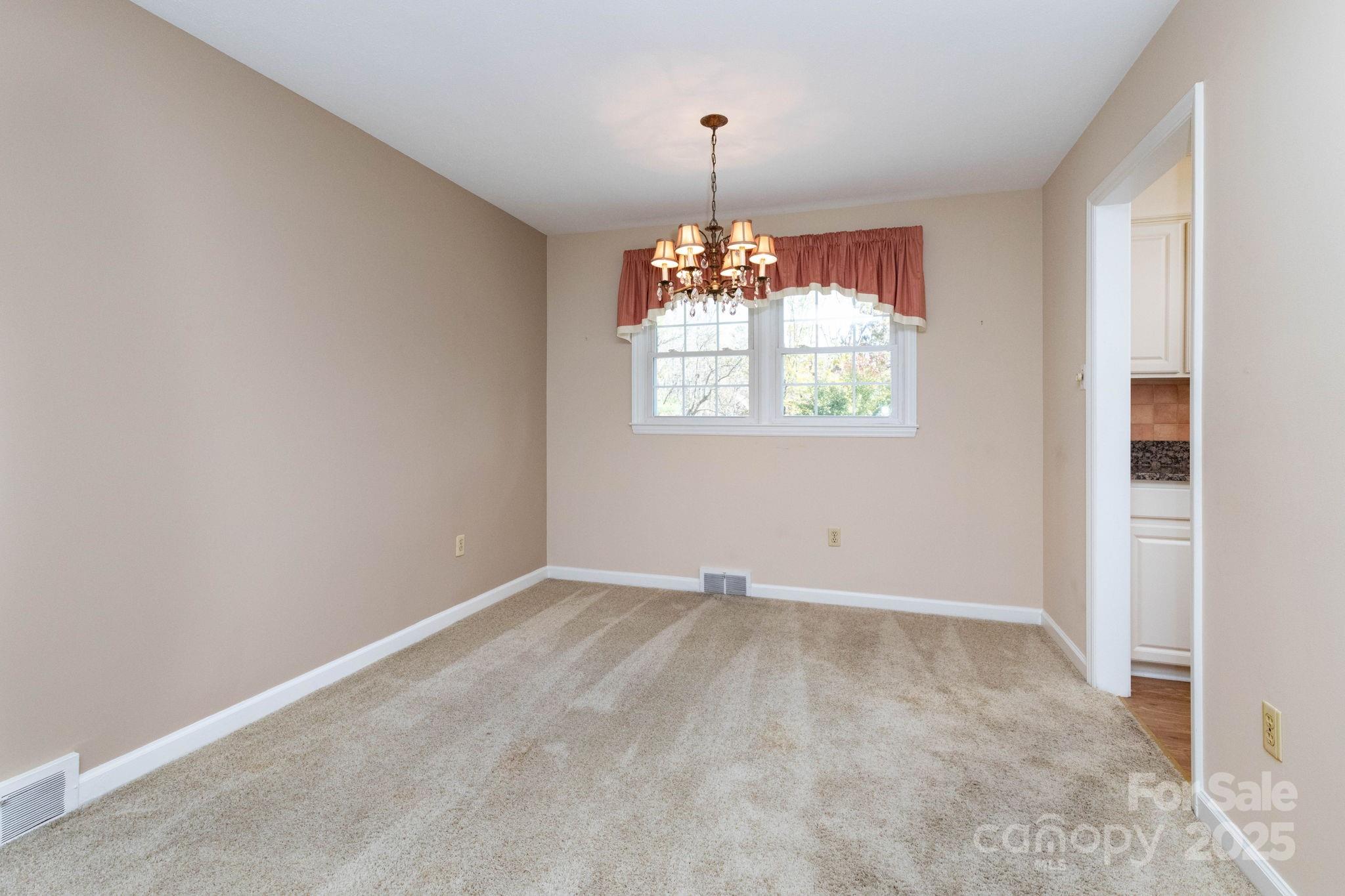 66 Gibson Road Asheville, NC 28804 - Photo 5 of 26 an empty room with window wooden floor and chandelier