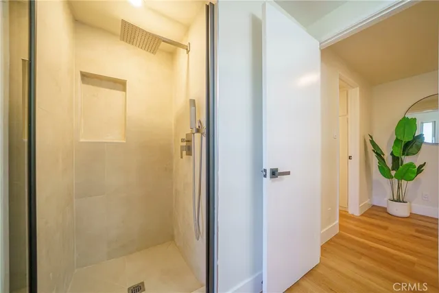 a view of a hallway with wooden floor and a bathroom