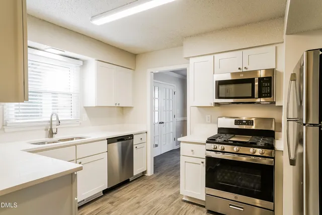a kitchen with stainless steel appliances a stove a microwave a sink and cabinets