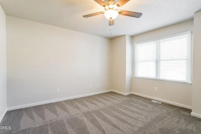 an empty room with a window and a fan