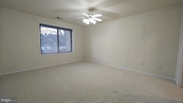 an empty room with windows and chandelier fan