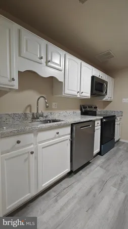a kitchen with granite countertop a sink cabinets and stainless steel appliances