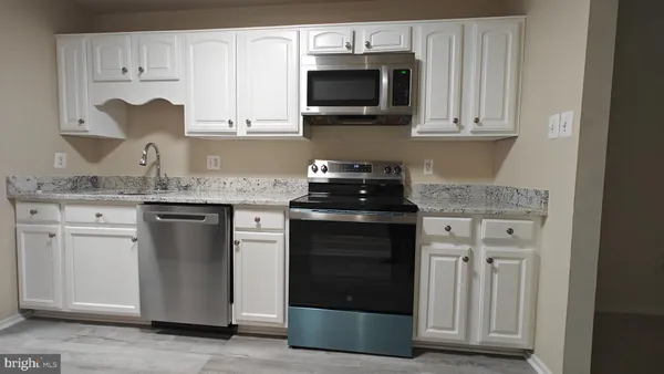 a kitchen with stainless steel appliances granite countertop white cabinets and a stove
