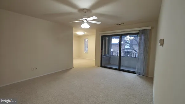 an empty room with a chandelier fan and windows