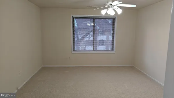an empty room with a chandelier fan and window