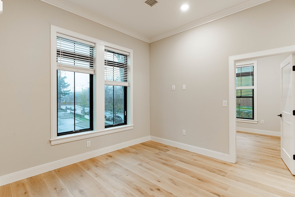 157 Everett Street, Unit 201 Boston, MA 02134 - Photo 5 of 8 an empty room with wooden floor and windows