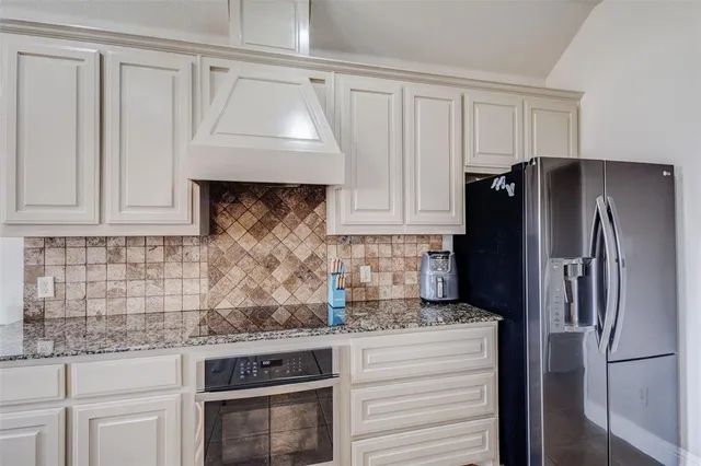 a kitchen with granite countertop a refrigerator sink and cabinets