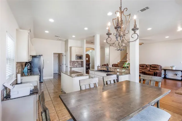 an open kitchen with granite countertop a table chairs stove and refrigerator