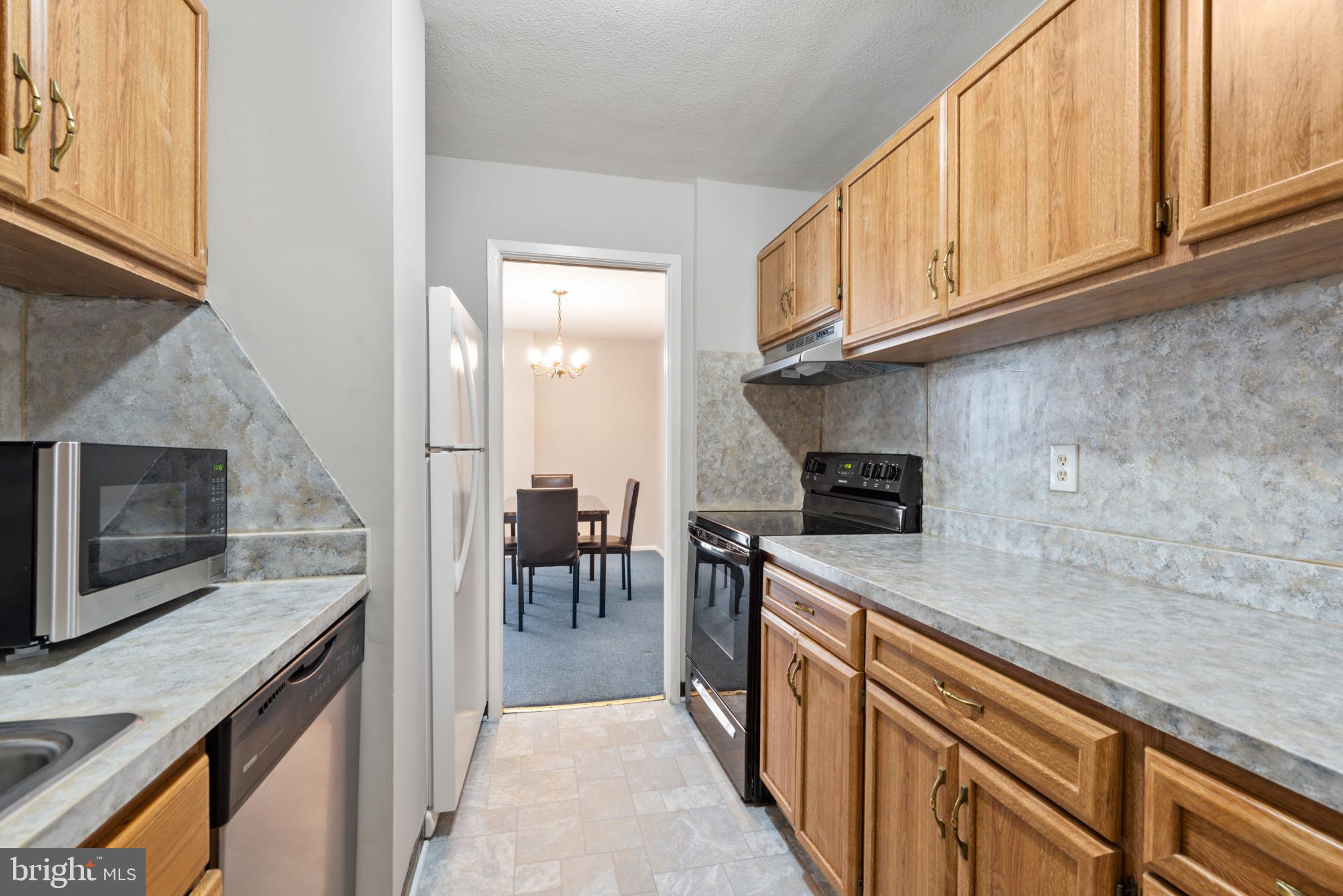 1 East University Parkway, Unit 304 Baltimore, MD 21218 - Photo 11 of 18 a kitchen with stainless steel appliances granite countertop a stove a sink and a microwave