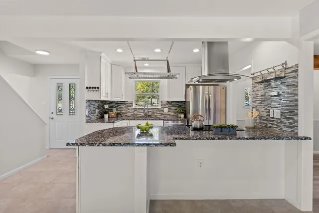 a kitchen with kitchen island granite countertop a stove a sink and a refrigerator