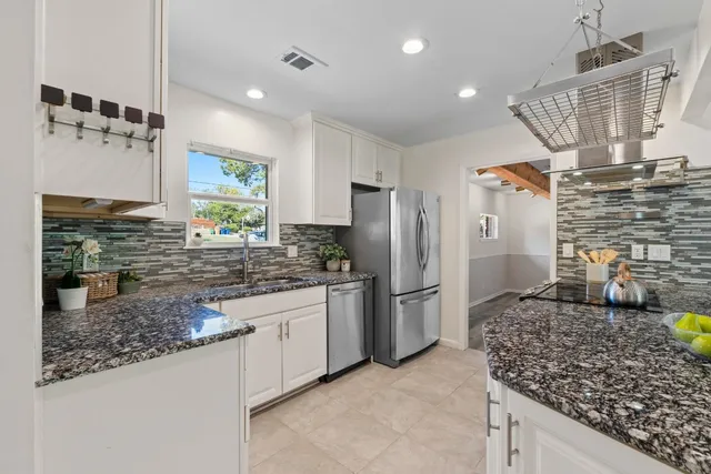 a kitchen with stainless steel appliances granite countertop a sink a stove and a refrigerator