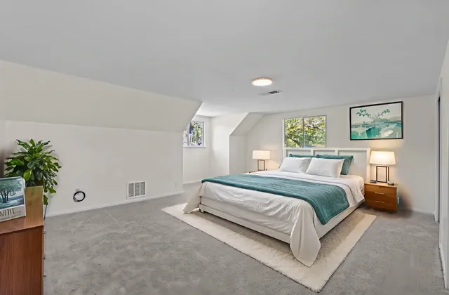 a spacious bedroom with a bed and a potted plant