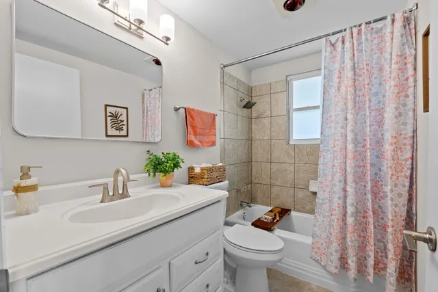 a bathroom with a sink a toilet a shower curtain and a mirror