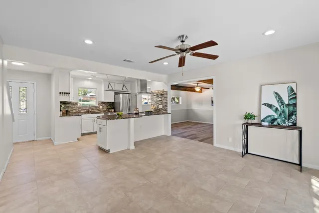 a view of kitchen with stainless steel appliances kitchen island a refrigerator sink and white cabinets