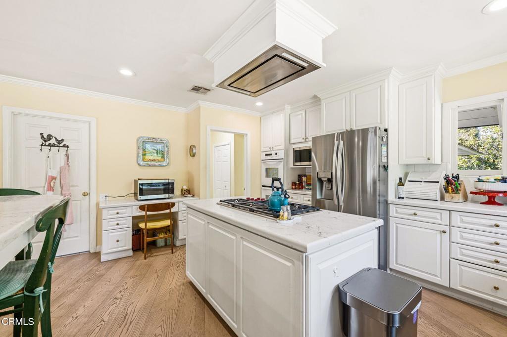 17933 Osborne Street Northridge, CA 91325 - Photo 9 of 33 a kitchen with a refrigerator a stove and a dining table with wooden floor