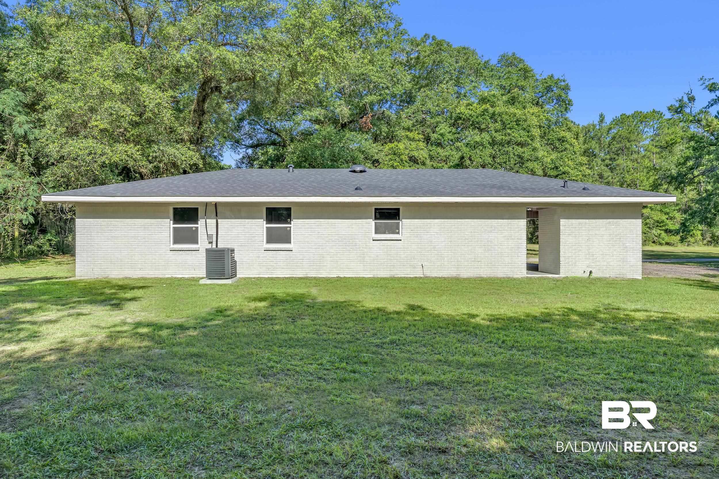 2712 Shelton Beach Rd Extension Mobile, AL 36613 - Photo 21 of 24 Stucco exterior with a dark shingle roof and white trim, featuring multiple windows and a central air conditioning unit