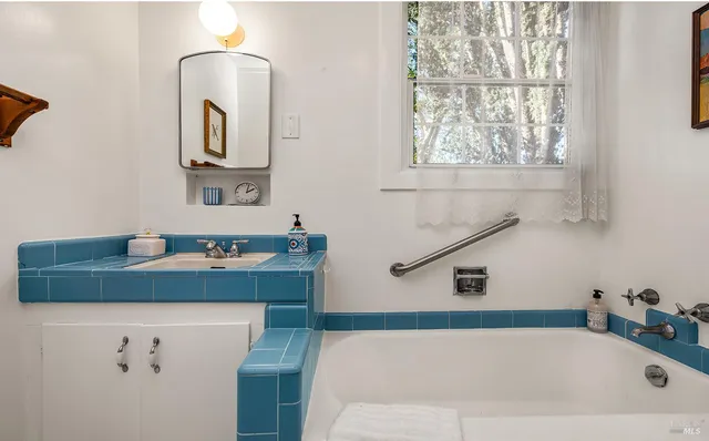 a bathroom with a tub sink and mirror