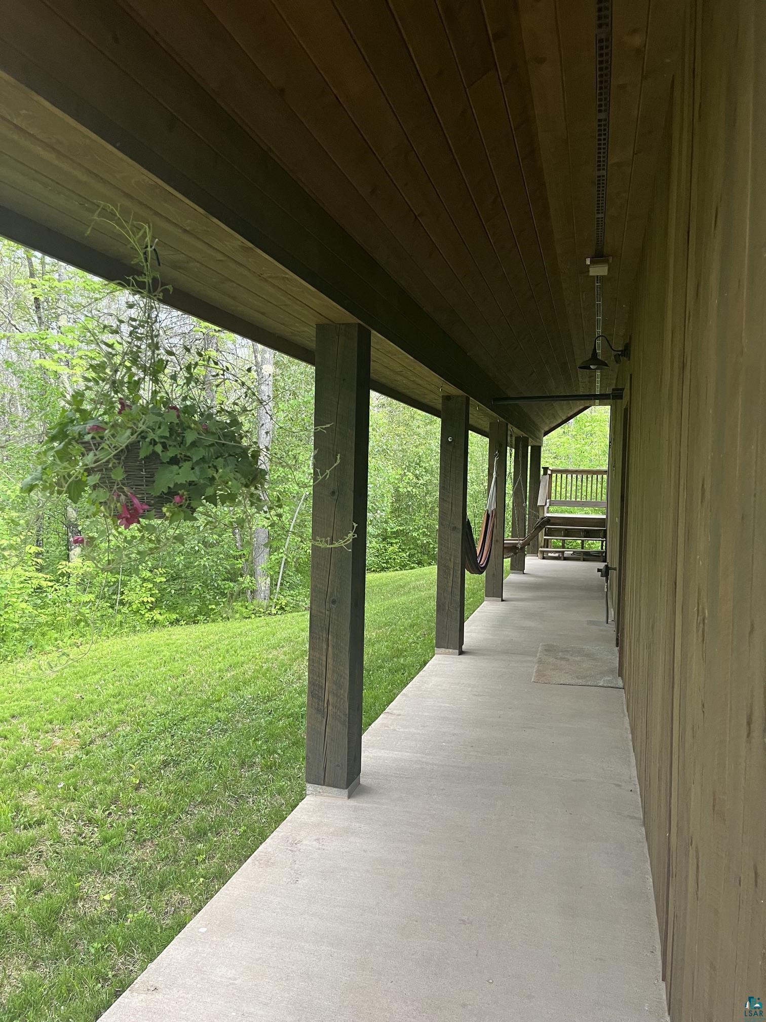 70745 Range Line Road Iron River, WI 54847 - Photo 34 of 40 Covered concrete porch with wood-clad ceiling, exposed wood support beams, and exterior wall siding