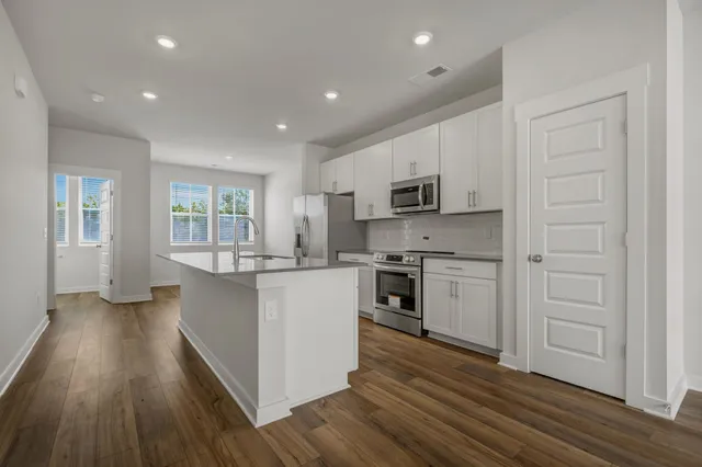 a kitchen with cabinets wooden floor and stainless steel appliances