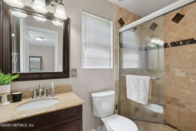 a bathroom with a granite countertop sink toilet a mirror and shower