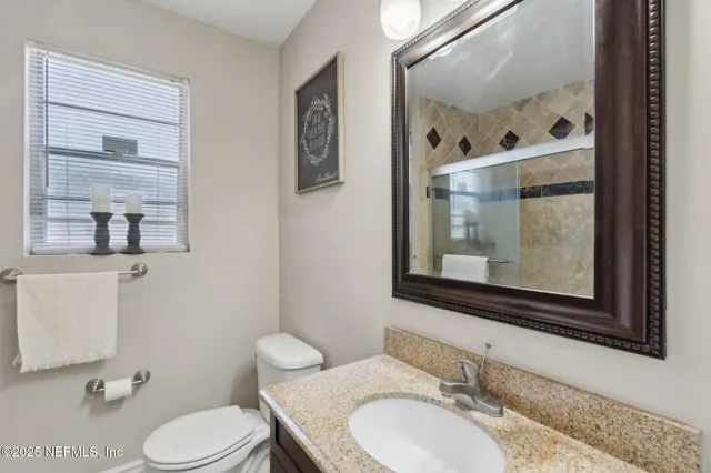 a bathroom with a granite countertop toilet sink and mirror