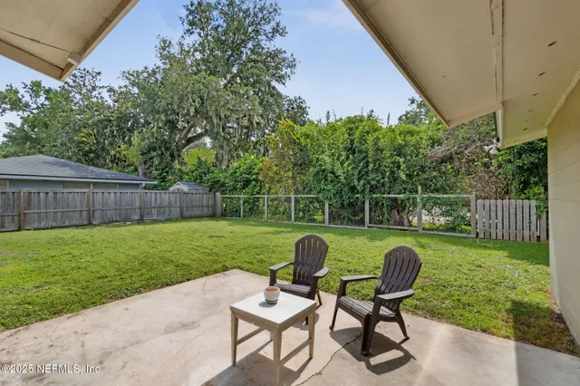 a view of a chair and table in the back yard of the house
