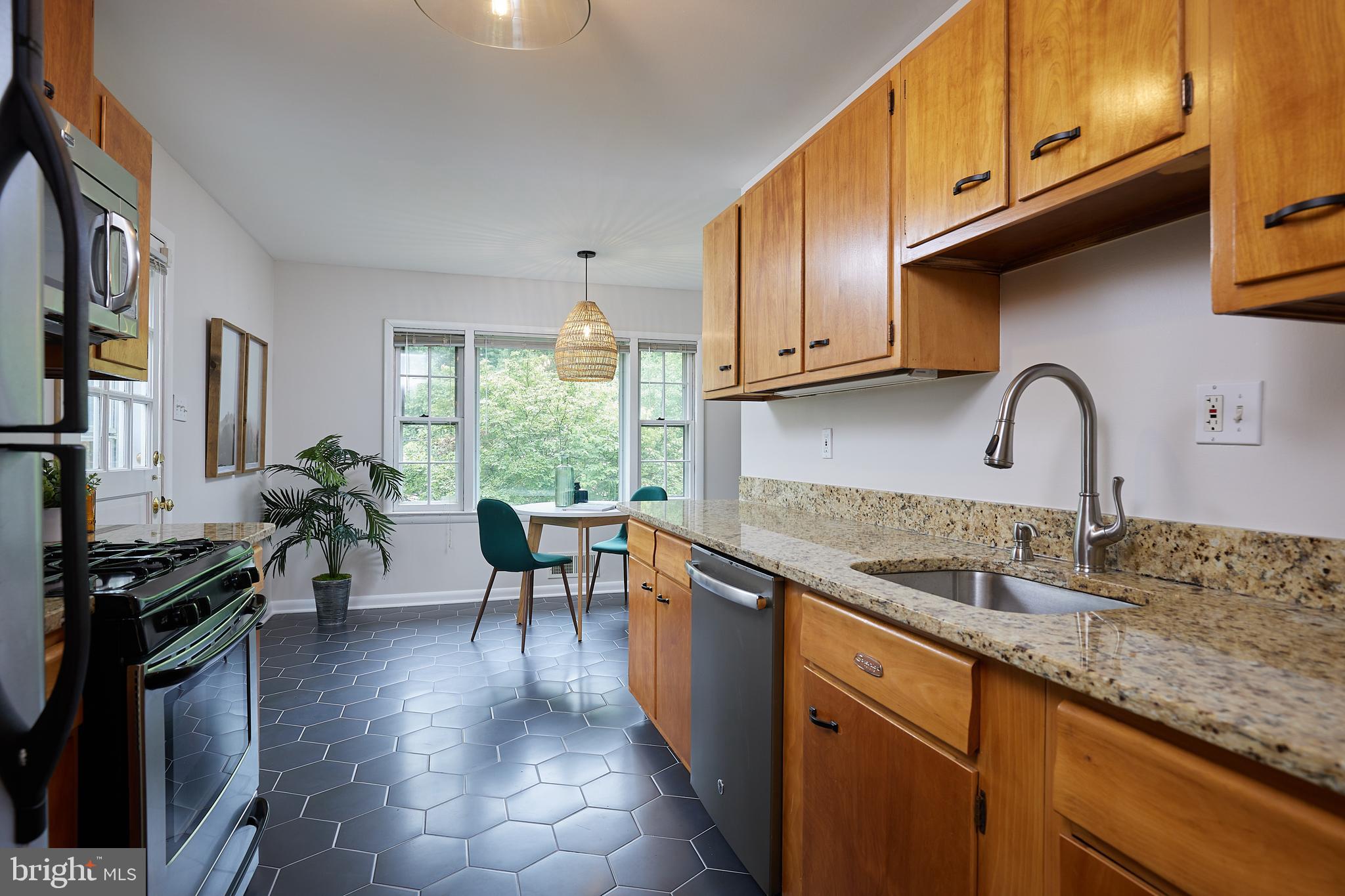 10611 Glenwild Road Silver Spring, MD 20901 - Photo 10 of 39 a kitchen with granite countertop a stove a sink a dining table and chairs