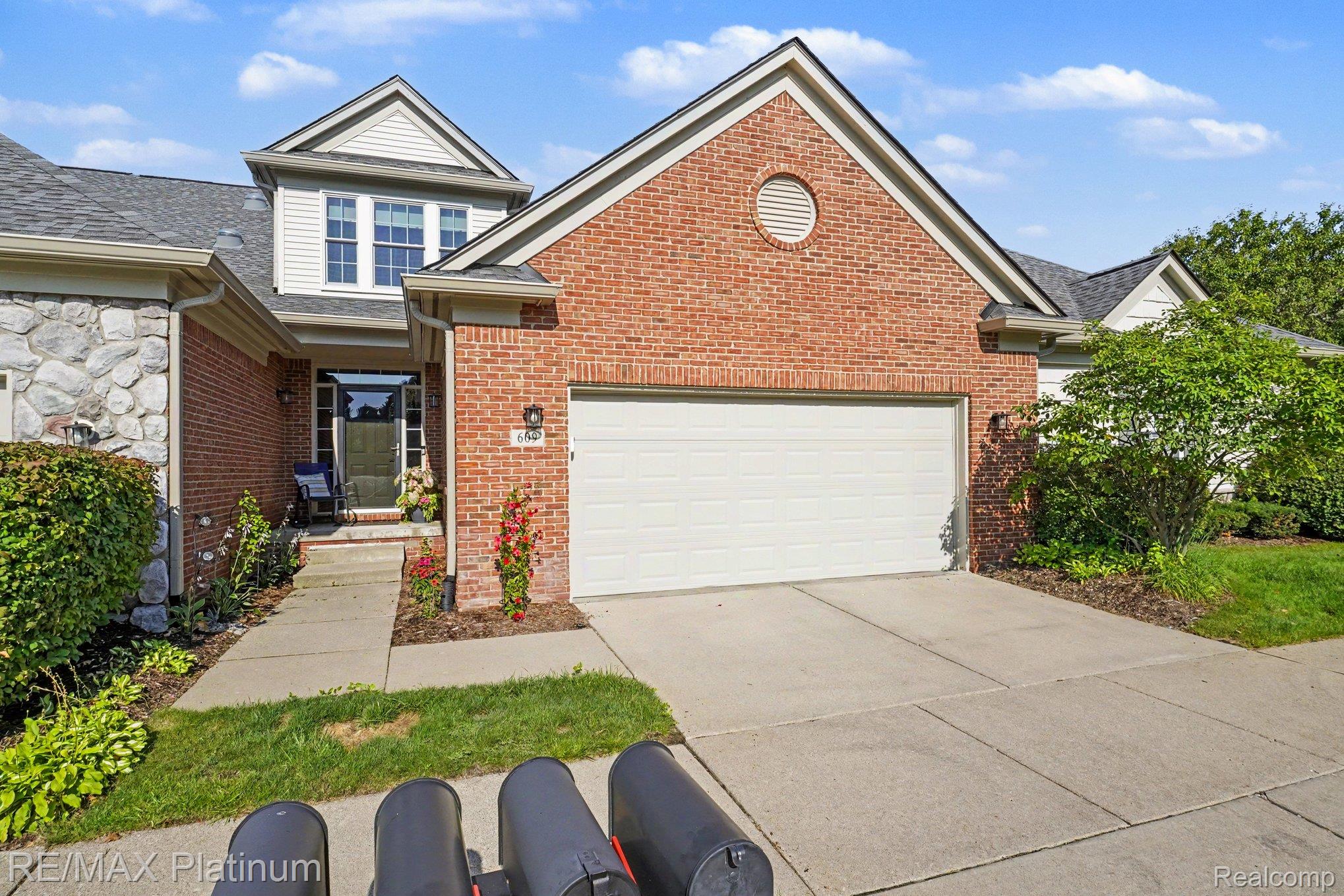 609 Telya Ridge Milford, MI 48381 - Photo 2 of 28 Brick and stone facade featuring a two-car garage, concrete driveway, and front entryway with sidelights
