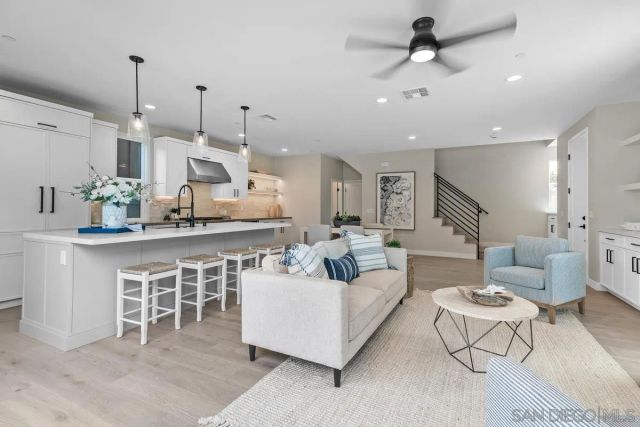 a living room with furniture kitchen view and a chandelier