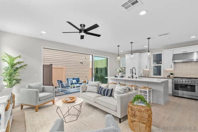 a living room with furniture kitchen view and a large window