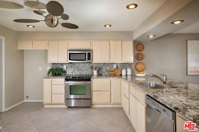 a kitchen with kitchen island granite countertop a sink stainless steel appliances and cabinets