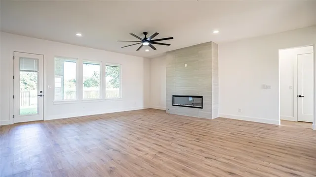 an empty room with wooden floor a ceiling fan and windows