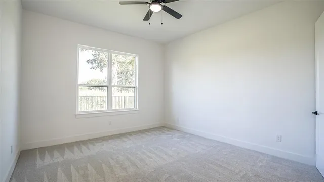an empty room with chandelier fan and windows