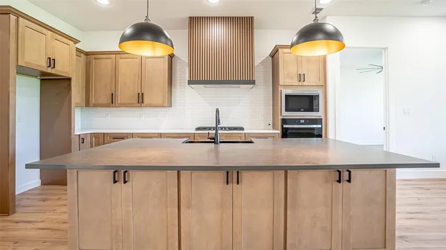 a kitchen with stainless steel appliances granite countertop a sink a stove and a wooden cabinets