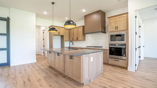 a kitchen with stainless steel appliances granite countertop a refrigerator a oven and a wooden floors