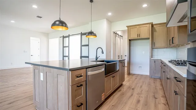 a kitchen with stainless steel appliances granite countertop a sink a stove and a wooden floors