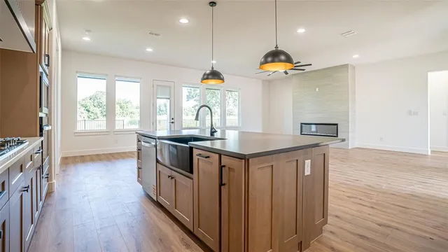 a kitchen with stainless steel appliances granite countertop a sink a stove and a wooden floors