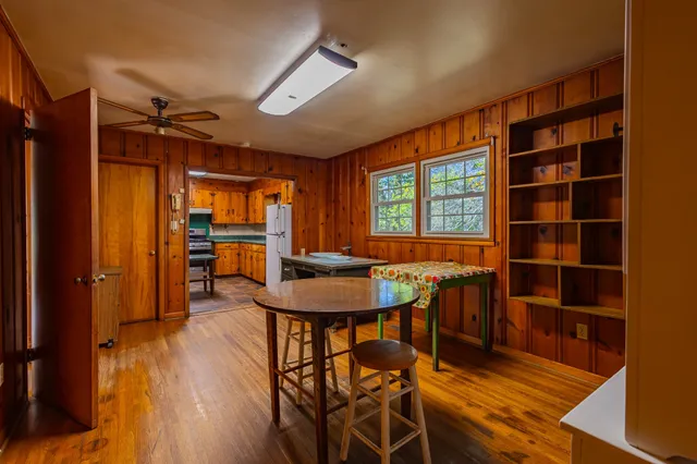 a view of a room with wooden floor a ceiling fan and windows