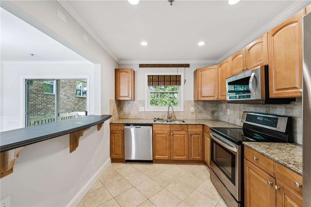 2825 Northeast Expressway, Unit F3 Atlanta, GA 30345 - Photo 15 of 45 a kitchen with stainless steel appliances granite countertop wooden cabinets a stove a sink and a window