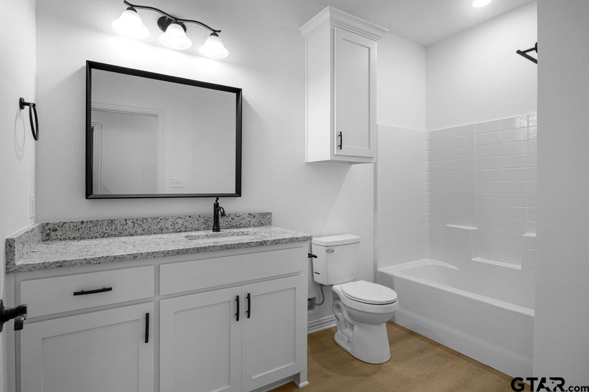 1610 West Barrett Street Tyler, TX 75702 - Photo 13 of 32 a bathroom with a granite countertop toilet a sink and a mirror